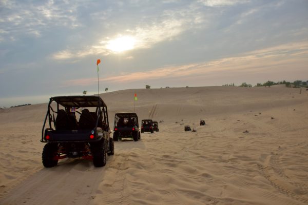 a truck that is driving down the beach