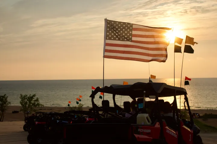 ATVs with American flag at sunset on a beach overlooking the ocean.