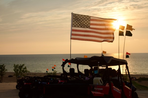 ATVs with American flag at sunset on a beach overlooking the ocean.